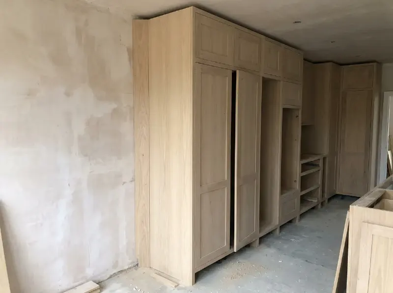Hoge keukenkasten die tot tegen het plafond lopen met een op maat gezaagd paneel tegen de muur